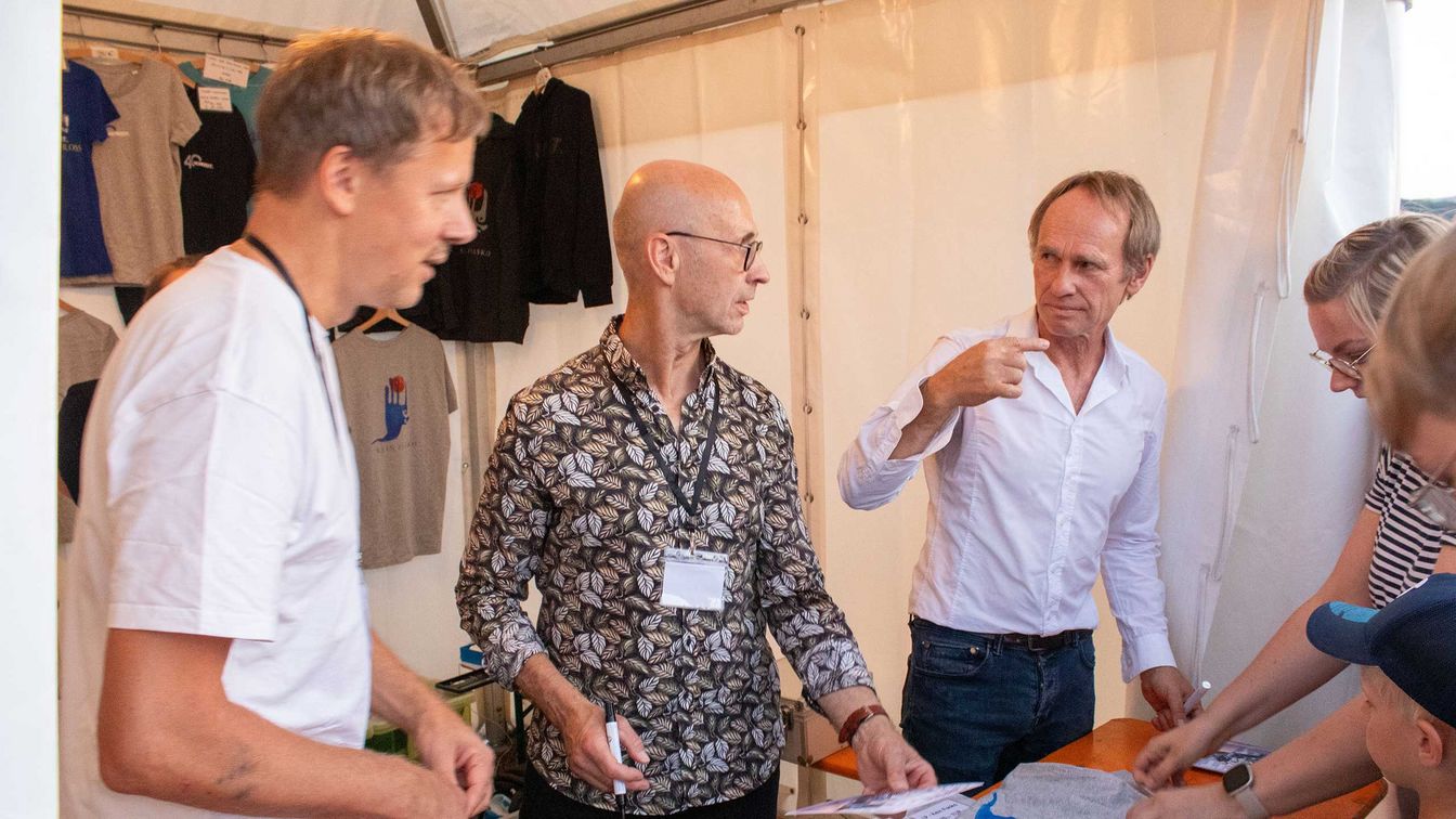 Mitglieder der Band Keimzeit stehen an einem Merchstand zum MDR Harz Open Air 2024 im Bürgerpark Wernigerode