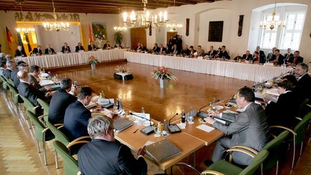 Personen sitzen während einer Tagung im Rathaussaal Wernigerode an Tischen, die zu einem Quadrat gestellt sind.