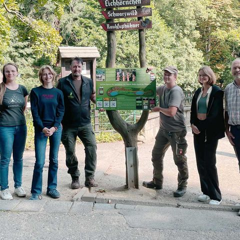 Zur Eröffnung der Rallye durch den Wildpark Christianental steht eine Gruppe von Personen und hält ein Schild in der Mitte.