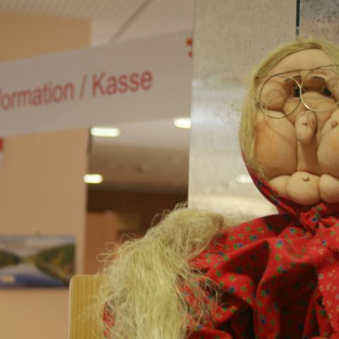 Eine Souvenirhexe sitzt auf dem Tresen der Tourist-Information in Wernigerode