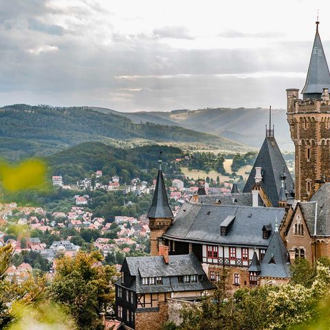 Der Blick geht vom Agnesberg zum Schloss Wernigerode mit der Stadt und den Bergen des Harzes im Hintergrund.