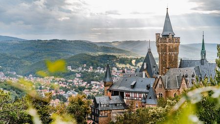 Der Blick geht vom Agnesberg zum Schloss Wernigerode mit der Stadt und den Bergen des Harzes im Hintergrund.