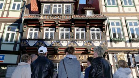 Eine Reisegruppe steht während einer Stadtführung vor dem Cafe Wien in Wernigerode.