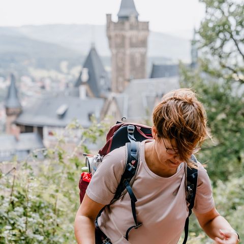 Eine Person wandert während der 24h-Wandertrophy den Agnesberg in Wernigerode hinauf. Im Hintergrund ist das Schloss Wernigerode zu erkennen.