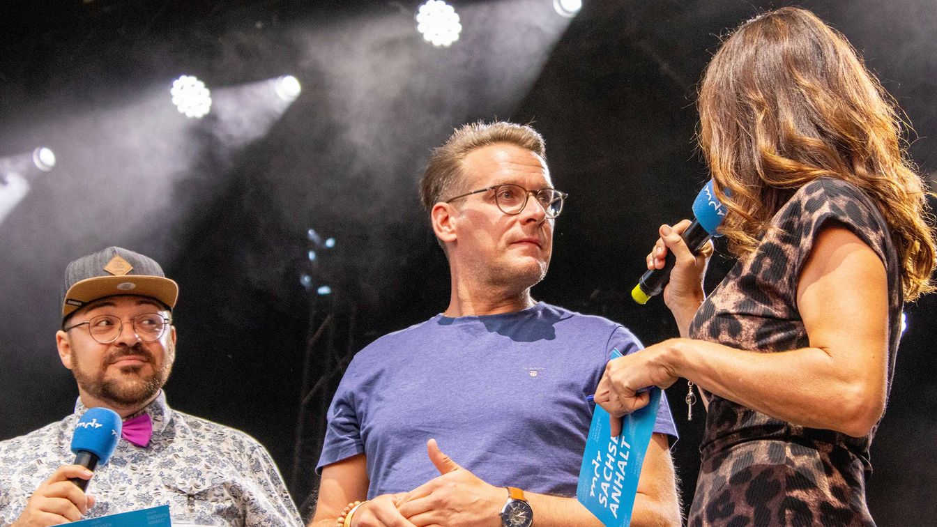 Der OB Tobias Kascha steht mit den beiden Moderierenden auf der Bühne des MDR Harz Open Air 2024