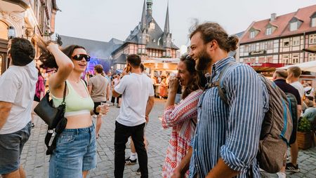 Besucher des Rathausfest in Wernigerode stehen auf dem Marktplatz und unterhalten sich.