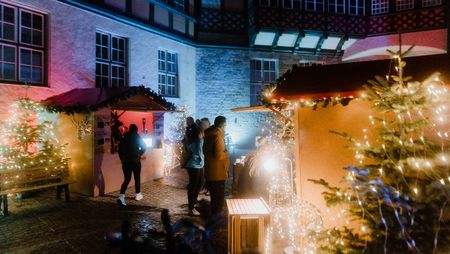 Personen stehen vor einer Hütte zur Adventszeit im Rathausinnenhof Wernigerode