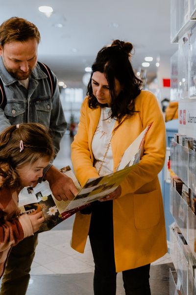 Eine Familie steht vor der Prospektauslage in der Tourist-Information Wernigerode.