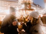 Ein Paar prostet sich mit Glühweinbechern auf dem Weihnachtsmarkt in Wernigerode zu.