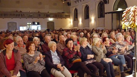 Publikum sitzt in Stuhlreihen vor der Bühne im Fürstlichen Marstall Wernigerode und applaudiert den Künstlern.